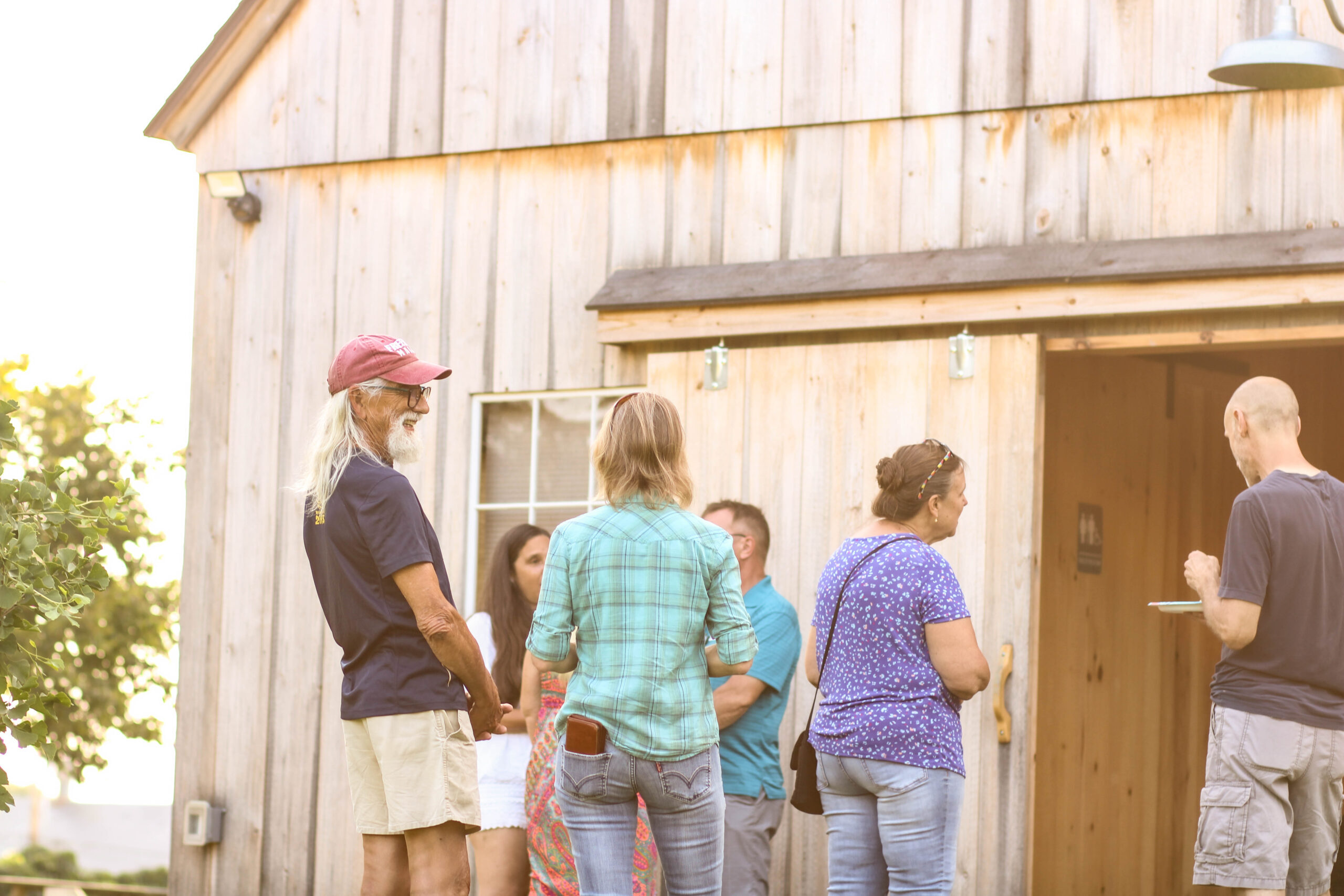 People chatting outside of a barn in the sun